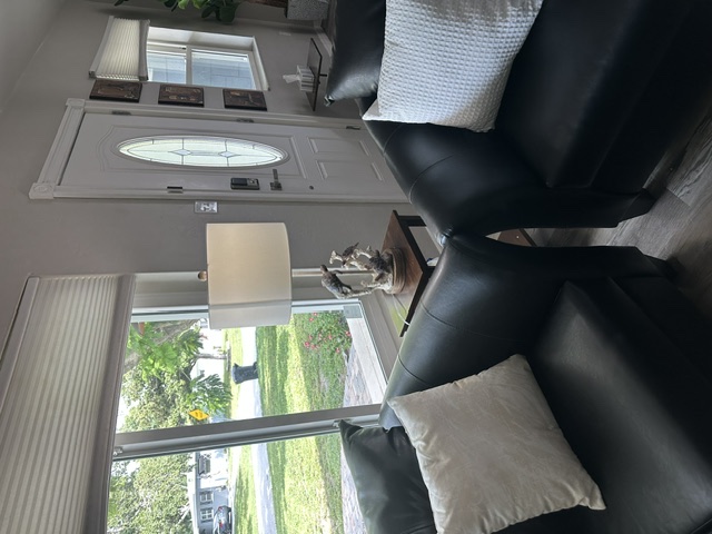Two black leather armchairs beside a bright front window and the front door, with a lamp on a side table