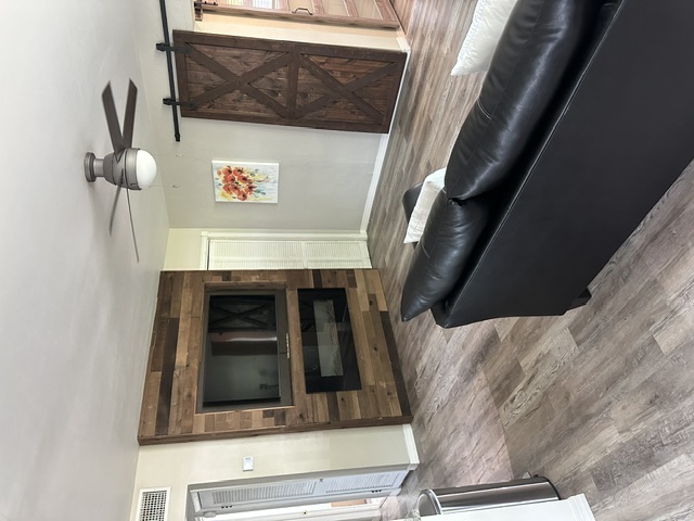 Living room with a wood-panel accent wall, electric fireplace, mounted television, and a sliding barn door