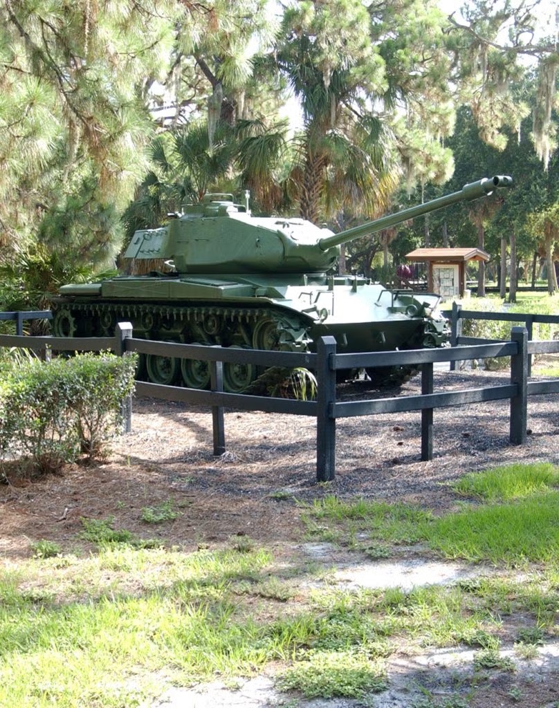 Stone entrance wall engraved War Veterans' Memorial Park, A Pinellas County Park, surrounded by palms and pines